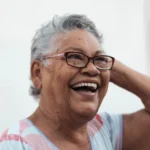 Elegant woman over 60 with a tousled silver messy haircut smiling in soft natural light