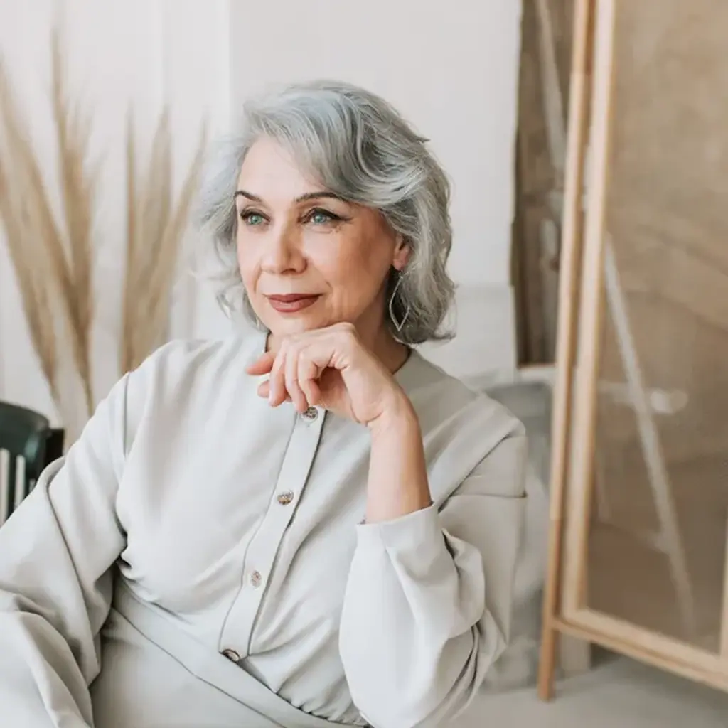Shoulder length gray layered hair with a deep side part