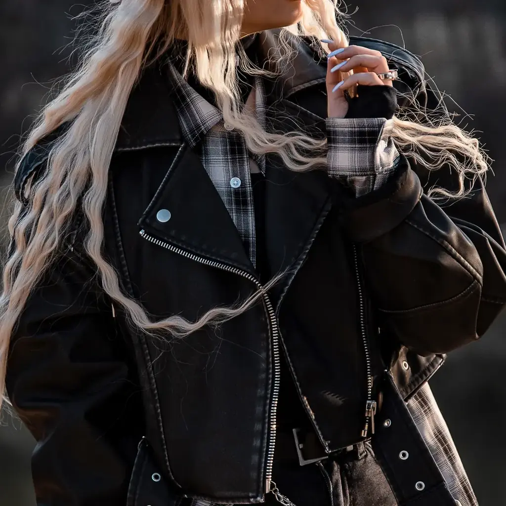 Woman in a black leather biker jacket over a plaid shirt, 80s punk inspired outfit
