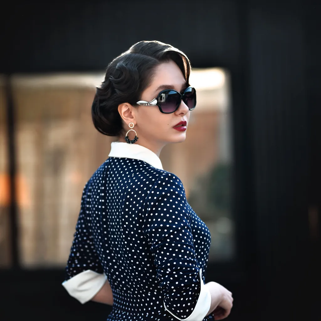 Woman in a polka dot dress with white collar and retro sunglasses, rockabilly 80s outfit