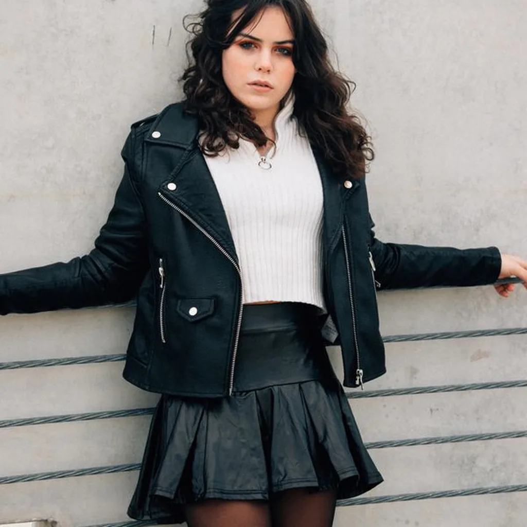 Woman in a black leather jacket and leather mini skirt with white top, 80s rock outfit