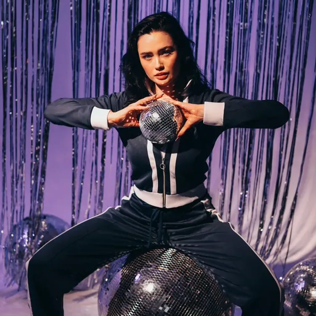 Woman in a disco party outfit holding a glitter ball, Studio 54 inspired glam look
